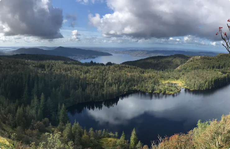 forested mountains and clear lakes under blue sky and clouds